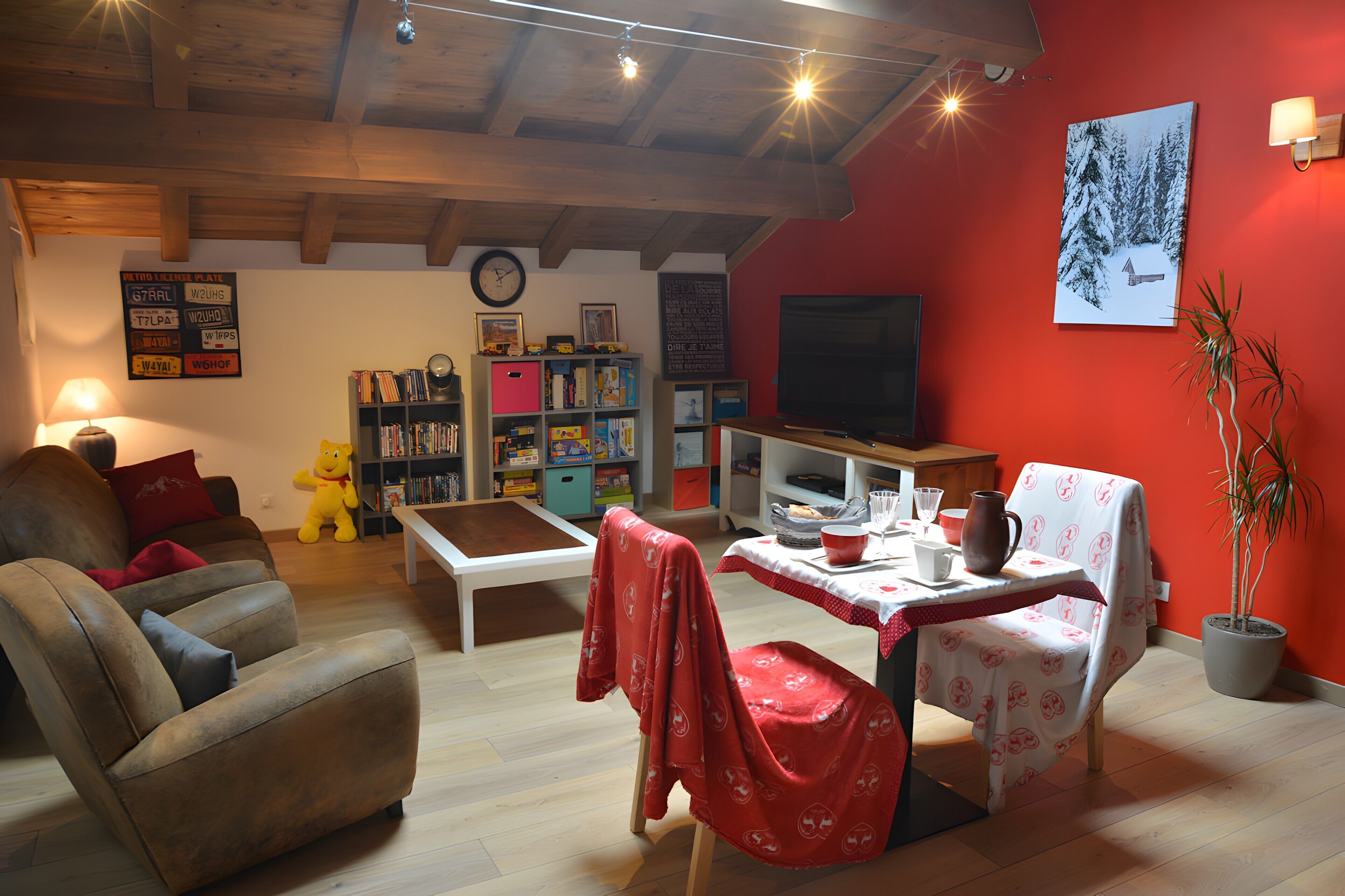 A cozy living room with a sofa, a table with a red tablecloth, a bookshelf, a television, and a potted plant.