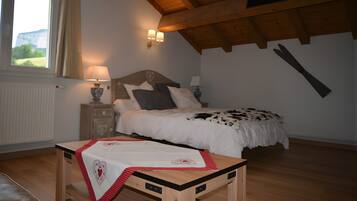 A bedroom with a wooden ceiling, a bed with a cowhide blanket, a bedside table with a lamp, and a window with curtains.