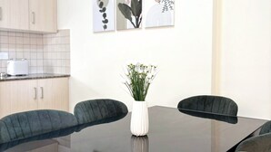 Een moderne eethoek met een glazen tafel, vier stoelen en een bloemenvaas.