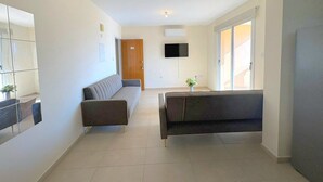Een moderne woonkamer met een bank, een salontafel en een flatscreen televisie aan de wand.