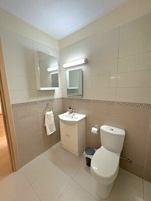 A bathroom with a toilet, sink, and mirror. - Sunrise Palette Suites - 1bedroom 6' way from sea (Xylofagou)