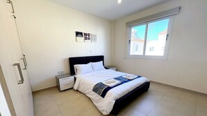 Una camera da letto con un letto, comodini, una finestra e una porta.