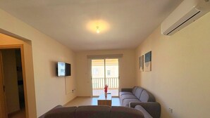 Un soggiorno con divano, televisore e balcone con vista.