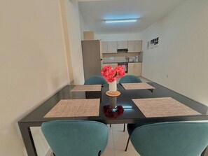 A dining area with a black table, teal chairs, and a vase with flowers. - Sunrise Palette Suites - 1bedroom 6' way from sea (Xylofagou)