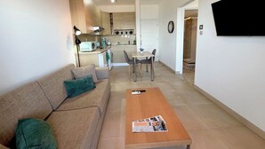 Een moderne woonkamer met een bank, salontafel en een eetgedeelte met stoelen en een tafel.