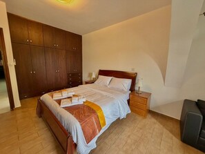 A bedroom with a bed, wooden wardrobe, bedside tables, and a lamp. - Villa Encanto - Private Heated Swimming Pool (Oroklini)
