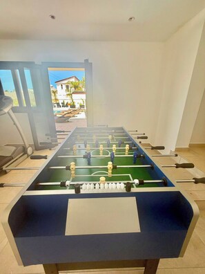 Ein Tischkicker in einem Raum mit Laufband und Blick auf ein Wohngebiet.
