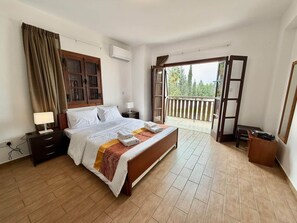 Ein Schlafzimmer mit Bett, Nachttischen, einem Fenster und einem Balkon.