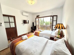 A hotel room with two beds, a TV, a balcony, and a lamp. - Villa Encanto - Private Heated Swimming Pool (Oroklini)