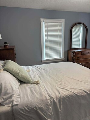 A bedroom with a bed, a dresser, a mirror, and a window with blinds. - Bright and Cheery 3 Bedroom Home w/Wifi and Laundry (Poultney)