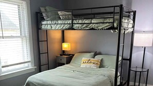Ein Schlafraum mit Etagenbetten, Nachttisch, Lampe und einem kleinen Beistelltisch.