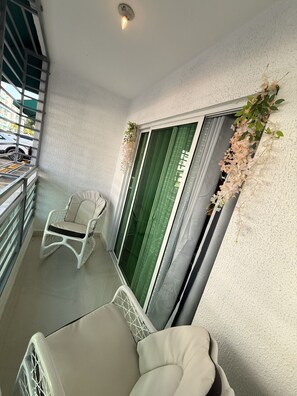 A balcony with a white chair, a second white chair, and a green curtain. - Blue ocean
First-floor two-bedroom apartment (Santo Domingo Este)