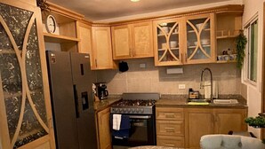 Una cocina con armarios de madera, un refrigerador de acero inoxidable, una estufa a gas y una encimera de granito.