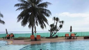 Ein Poolbereich mit gewölbter Kante, Liegestühlen und Palmen.