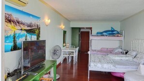 Ein Zimmer mit Etagenbetten, einem Schreibtisch, einem Stuhl, einem Fernseher und einem Bild an der Wand.