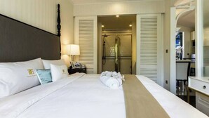 Hotelkamer met een groot bed, nachtkastje, lamp, douche en bureau met stoel.