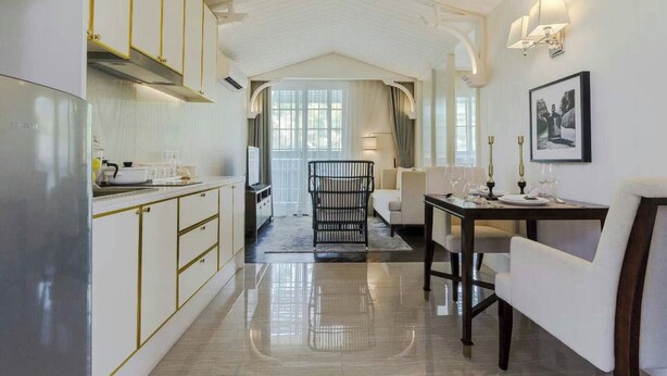 Een moderne keuken met witte kasten en een eethoek met een tafel voor vier personen.