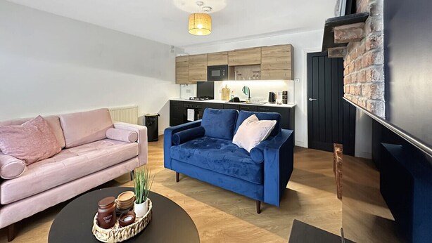 Un soggiorno moderno con un divano rosa, un divano blu e un tavolino da caffè con oggetti decorativi.