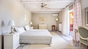 Une chambre à coucher avec un lit, des tables de chevet, une chaise, un ventilateur de plafond et une vue sur l’extérieur.