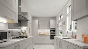 A modern kitchen with white cabinetry, stainless steel appliances, and a central island with a sink. - Relaxed Family Retreat in Kingston (Kingston Upon Thames)