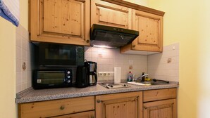 A kitchen with wooden cabinets, a microwave, a coffee maker, and a sink. - Apartment with Garden View (Spalt)