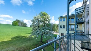 A building with a balcony, a tree with white blossoms, and a clear blue sky. - Apartment with Garden View (Spalt)