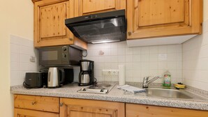 Eine Küche mit Holzausstattung, einer Mikrowelle, einer Kaffeemaschine und einem Spülbecken.