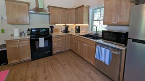 Cocina con armarios de madera, un refrigerador de acero inoxidable, un microondas, una estufa y un lavamanos.