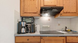 A kitchen with wooden cabinets, a built-in oven, a coffee maker, and a sink. - Apartment with Garden View K1 206 (Spalt)