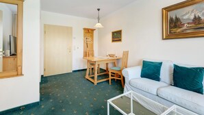 A room with a dining table, a sofa, a painting, and a door. - Apartment with Garden View K1 206 (Spalt)