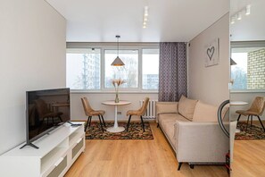 A modern living room with a TV, sofa, chairs, and a small table.
