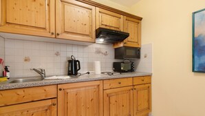Une cuisine avec des meubles de rangement en bois, un four à micro-ondes, un grille-pain et un évier.