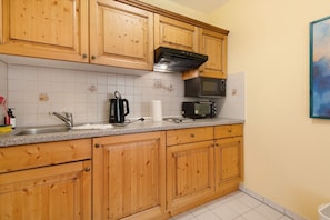 Eine Küche mit Holzschränken, einer Mikrowelle, einem Toaster und einem Spülbecken.