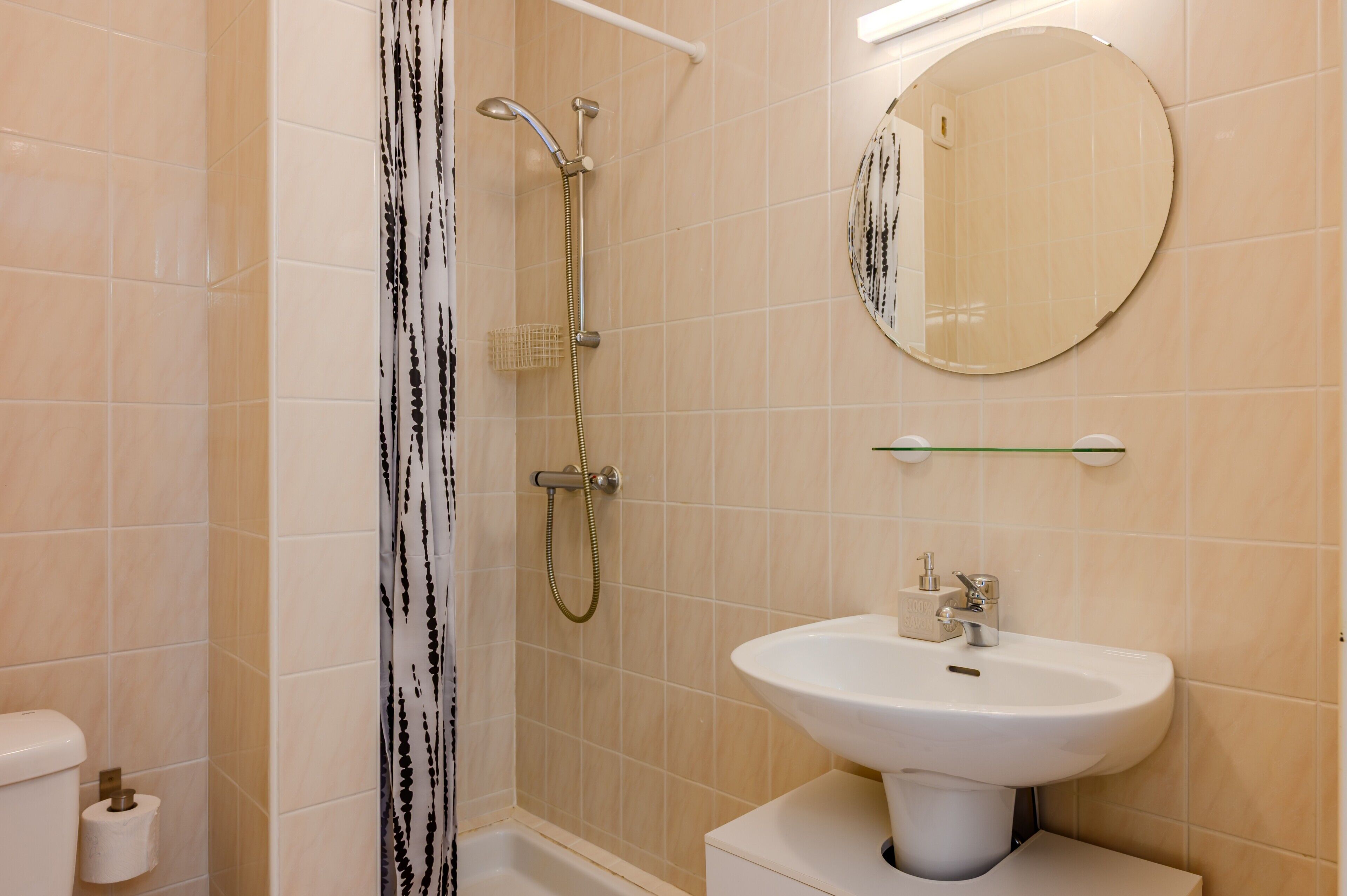 A bathroom with a shower, toilet, sink, and mirror.