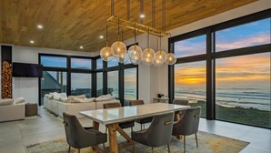 Un intérieur moderne avec un coin repas, de grandes fenêtres et une vue sur l’océan.