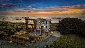 A modern two-story house with large windows, a covered outdoor area, and a view of the ocean. - Bandon Coast / Bandon Dunes, Ocean views & Hot Tub (Bandon)