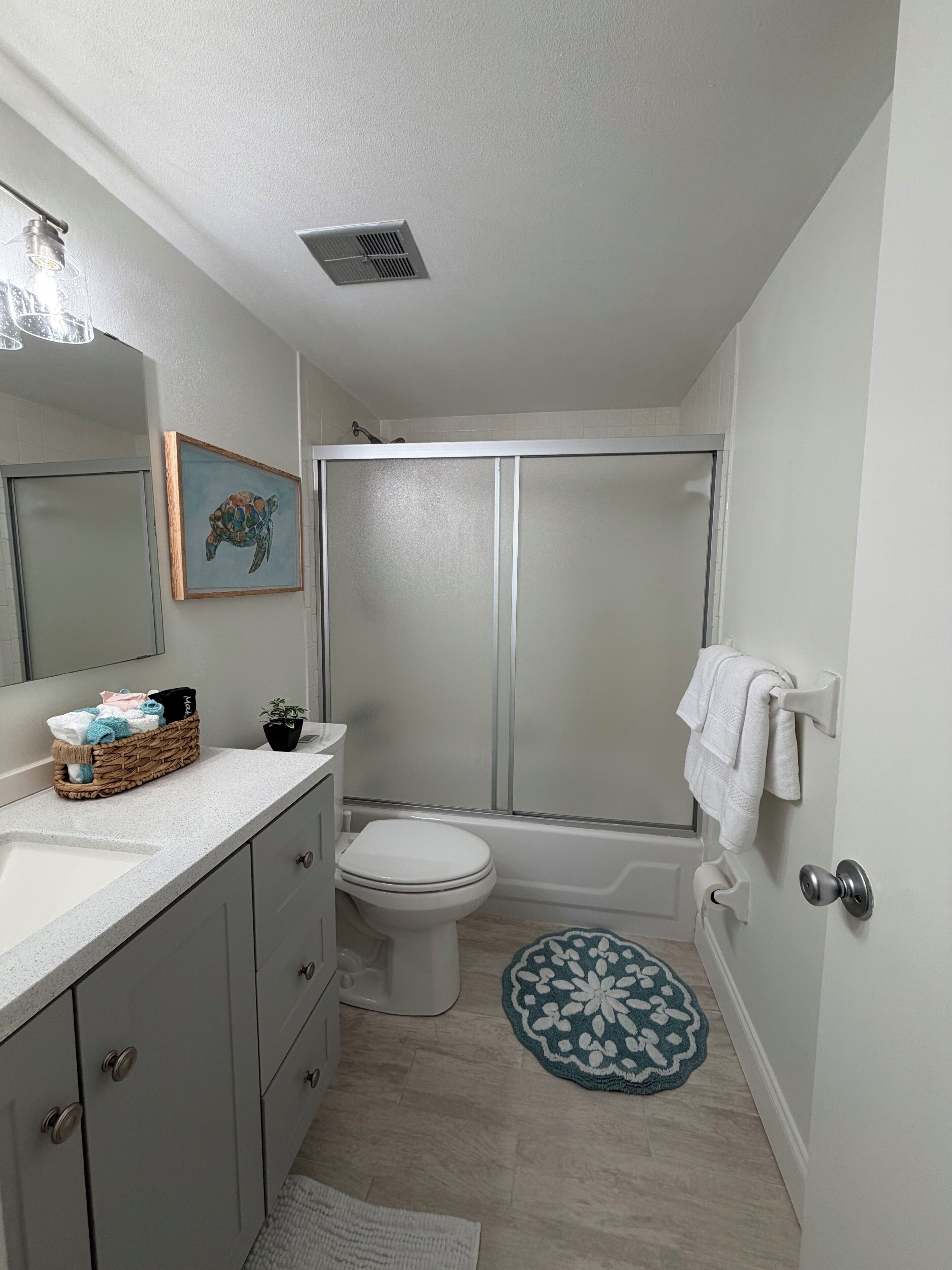 Une salle de bain équipée d’une douche, de toilettes, d’un lavabo et d’un tableau encadré au mur.
