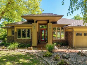Une maison à deux étages avec une façade en pierre, une porte rouge et un garage.