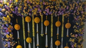 Eine dekorative Blumenanordnung mit hängenden Ornamenten und einer Wasserattraktion in der Mitte.