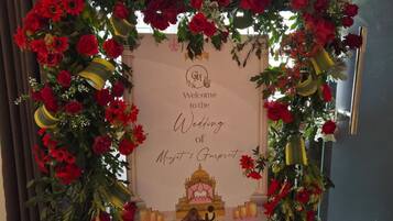 A wedding arch with red flowers and a welcome sign for the wedding of Minjit & Gurpreet.