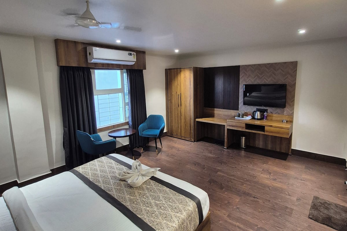 Habitación de hotel con una cama grande, un escritorio, dos sillas, un televisor y un equipo de aire acondicionado.