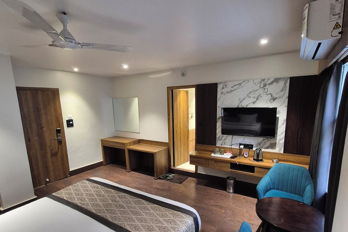 Una habitación de hotel moderna con una cama grande, un escritorio, un televisor y una zona de estar.