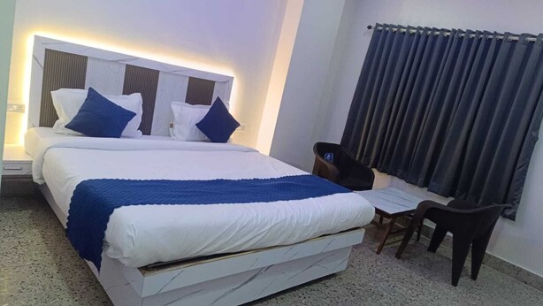 A hotel room with a large bed, a desk, and a chair. - HOTEL JAGAPATHI INTERNATIONAL (Vijayawada)