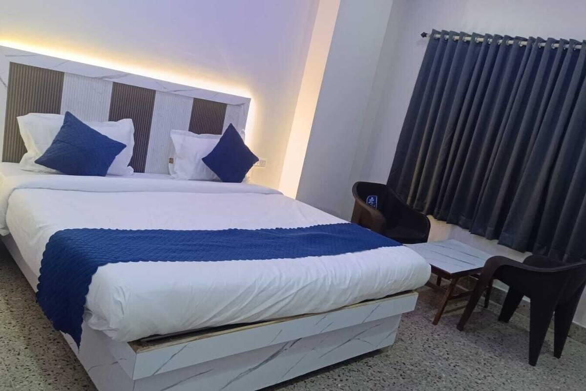 A hotel room with a large bed, a desk, and a chair.
