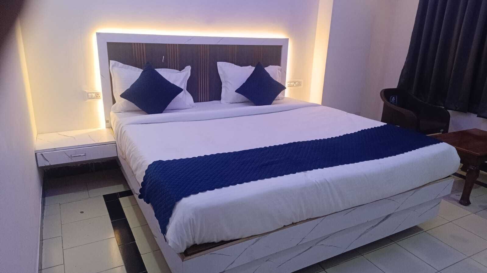 Ein ordentlich bezogenes Bett mit einer weiß-blauen Streifendecke, einem Holzkopfstück und zwei Kissen.