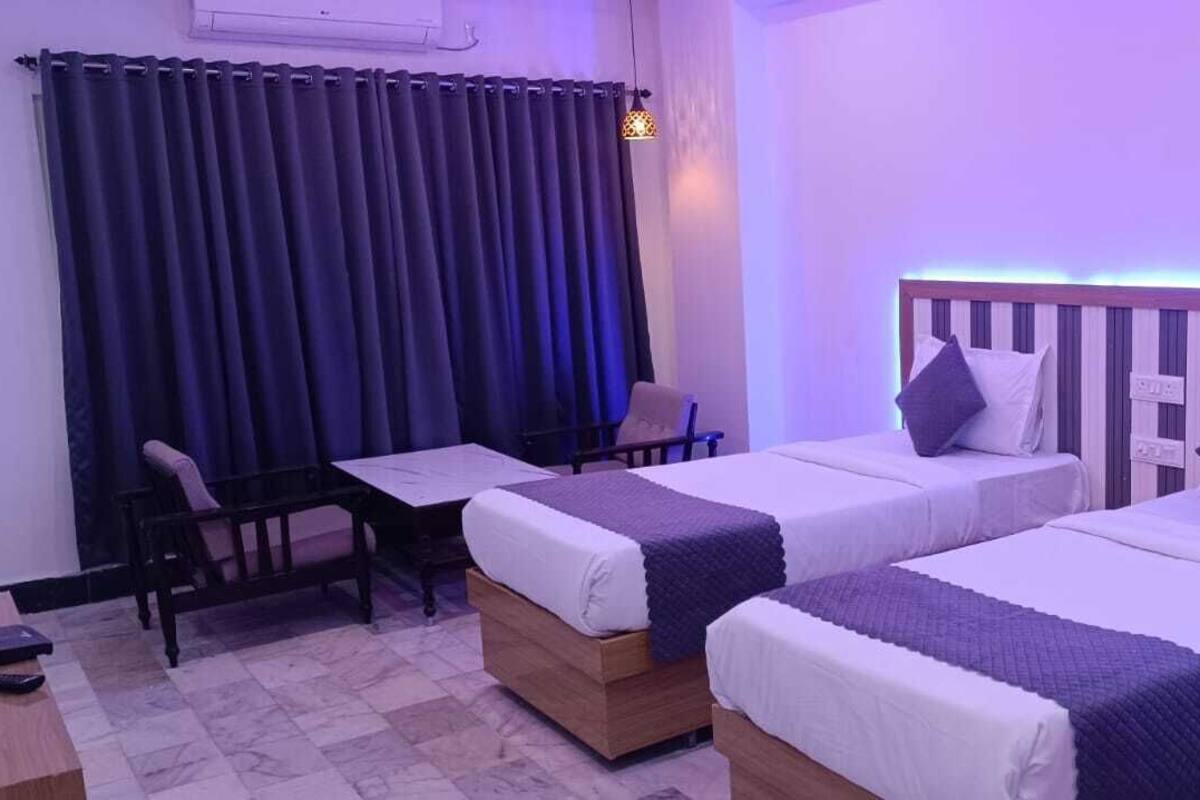 A hotel room with two single beds, a desk, and a chair.