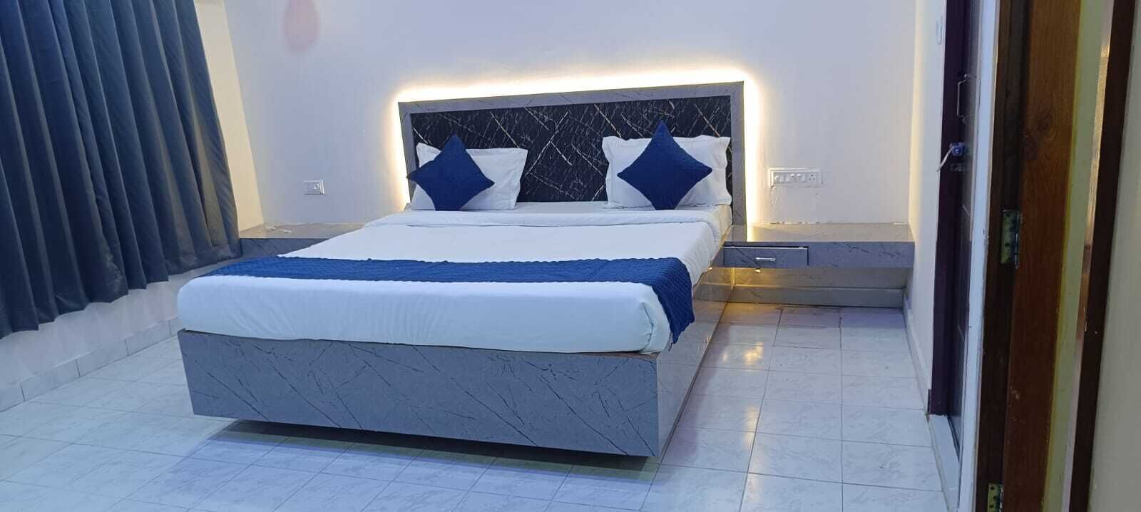 A modern bedroom with a large bed, a marble headboard, and a bedside table with a lamp.