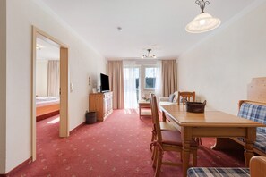 Une pièce comprenant un lit, un téléviseur, une table à manger avec des chaises et un canapé.
