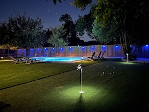 Ein Garten mit Pool, Liegestühlen und Putting-Green.