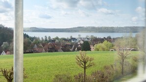 A rural landscape with a lake, houses, and a clear sky.